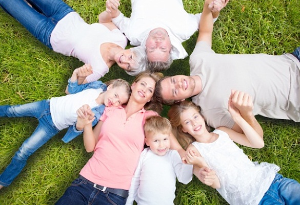 Eine Familie liegt im Kreis auf einer Wiese.